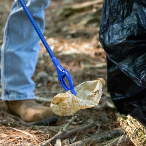 volunteer picks up trash from the shores of Glenville Lake
